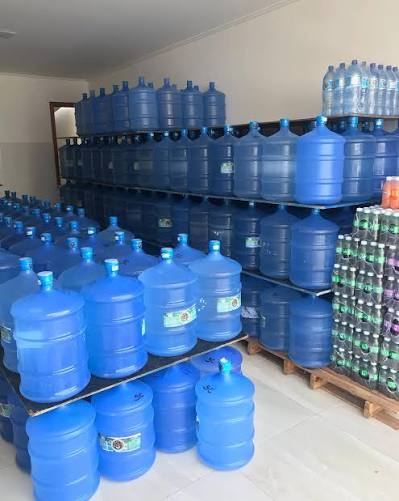 Galões de água de 20 litros empilhados no depósito de uma distribuidora